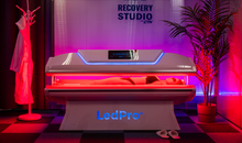 Load image into Gallery viewer, LED light therapy bed in a room labeled 'Recovery Studio' with 'LedPro' branding.